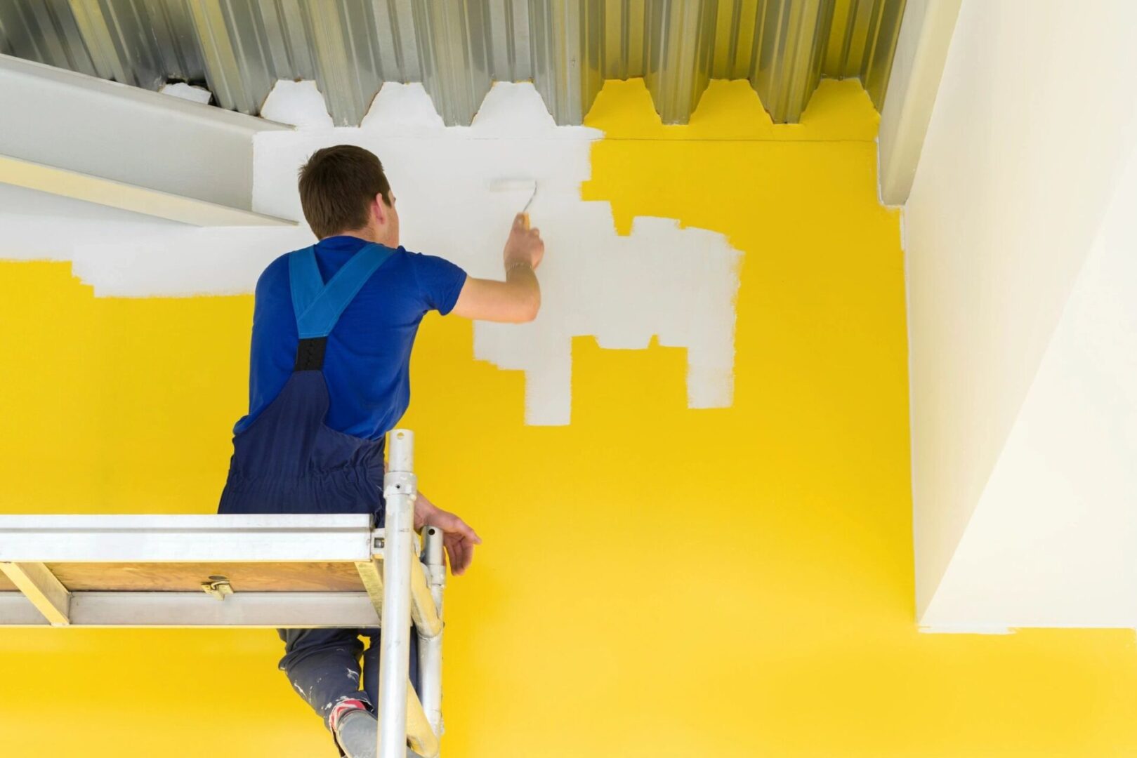 A man painting the wall of a room.